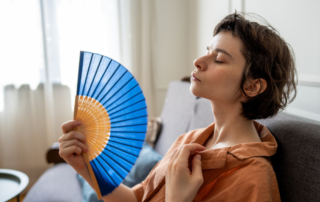 Middle-aged woman fanning herself due to a hot flash.