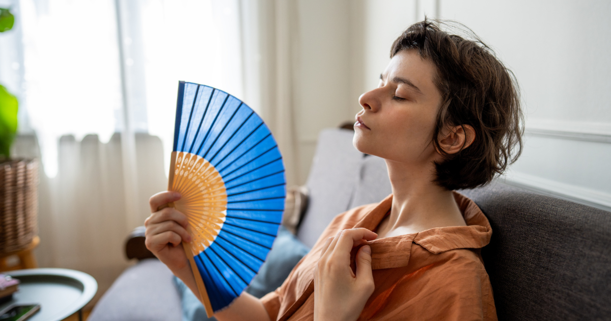Middle-aged woman fanning herself due to a hot flash.